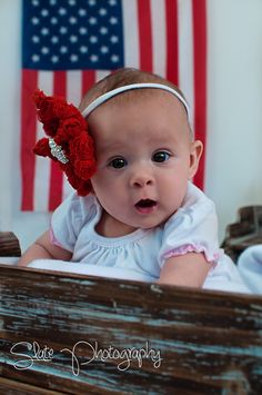 a baby girl with a red flower in her hair