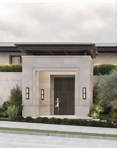 a woman is standing in the doorway of a modern house with greenery on either side