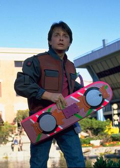 two young children are standing in front of a building and one boy is holding a skateboard