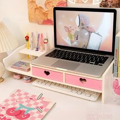 an open laptop computer sitting on top of a desk next to other office supplies and decorations