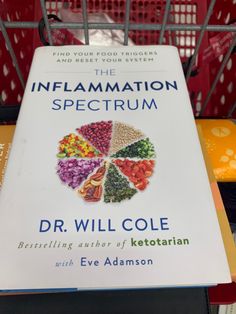 a book titled the inflamamation spectrum by dr will cole sits on top of a shopping cart