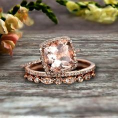 two wedding rings with an morganite in the center and diamonds on each band, sitting on a wooden surface