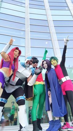 four people dressed in costumes posing for a photo outside an office building with their arms up