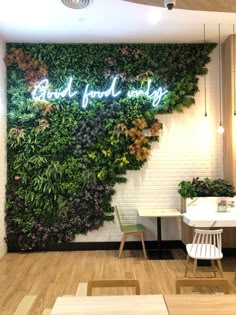 a green wall in the middle of a room with two chairs and a table next to it