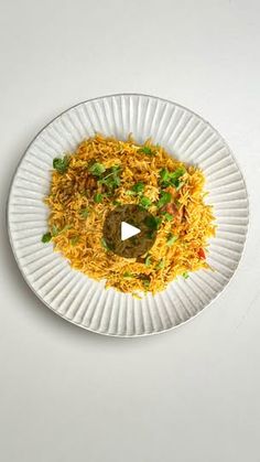 a white plate topped with yellow rice and veggies on top of a table