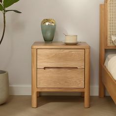 a bedroom with a bed, nightstand and potted plant on the side table next to it