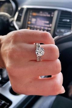 a woman's hand with a ring on it and a car steering wheel in the background