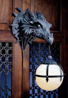 a dragon head mounted to the side of a wooden door next to a light fixture