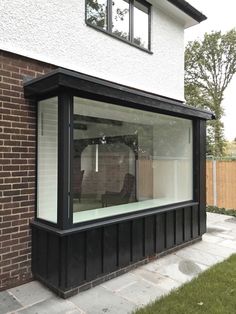 a black and white window sitting on the side of a brick building next to a grass covered yard