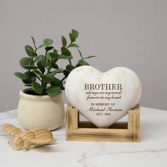 a heart shaped vase with a plant in it next to a plaque that says, brother always on my hand