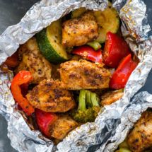 two foil packets filled with chicken and veggies