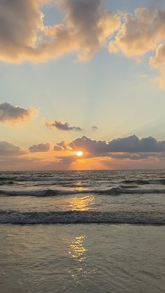 the sun is setting over the ocean with clouds in the sky and water on the beach