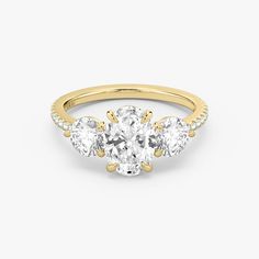 three stone engagement ring in yellow gold with diamonds on the sides and an oval cut diamond center