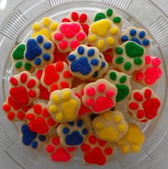 there is a bowl full of colorful dog paw cookies