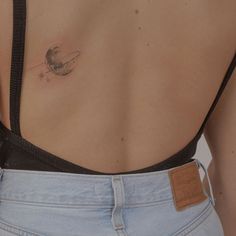 the back of a woman's stomach with a small tattoo on her left side