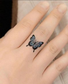 a woman's hand with a butterfly tattoo on the middle finger and an open ring