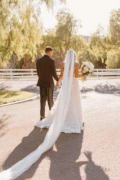 the bride and groom are walking down the street holding hands with each other as they hold hands