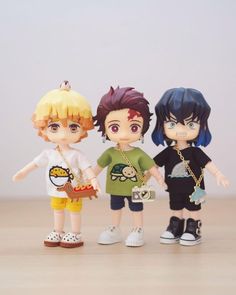 three anime dolls are standing next to each other on a wooden table with white walls in the background