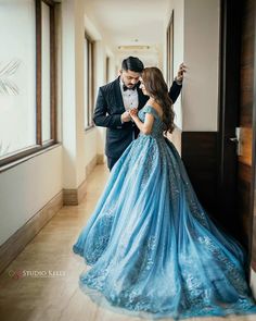 a man in a tuxedo standing next to a woman in a blue dress