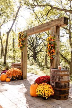 an outdoor ceremony with sunflowers, pumpkins and flowers on the ground next to barrels