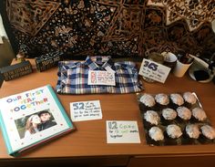 a table topped with cupcakes covered in frosting next to an open book