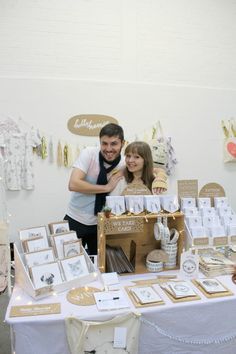 a man standing next to a woman in front of a table filled with pictures and cards