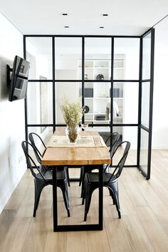 a dining room table with chairs and a vase on top of it in front of a glass wall