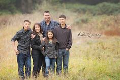 a family is posing for a photo in the tall grass with their arms around each other