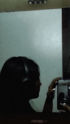 a woman taking a selfie in front of a mirror with headphones on her head