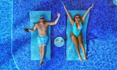 two people in swimsuits laying on their stomachs next to a swimming pool