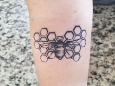 a black and white photo of a bee tattoo on the right leg, with honeycombs in the background