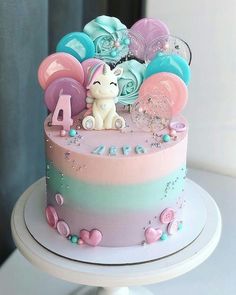 there is a cake decorated with pastel colors and decorations on the top, along with an animal figurine