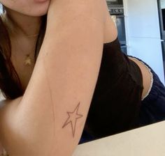 a woman with a star tattoo on her arm is sitting in front of a counter