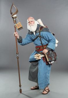 an old man with a long white beard is holding a staff and wearing blue clothing