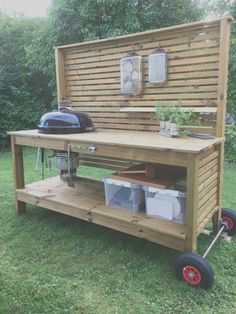 an outdoor bbq grill on wheels with potted plants and other items in the back