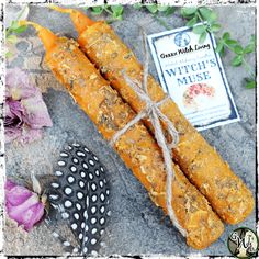 some kind of bread sticks tied up with twine and flowers on the ground next to a book