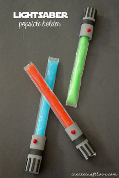 two lightsaber popsicle holders made out of plastic wrappers and colored paper