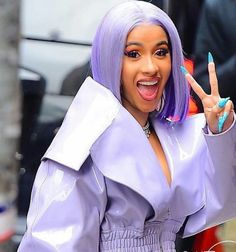 a woman with purple hair making the peace sign