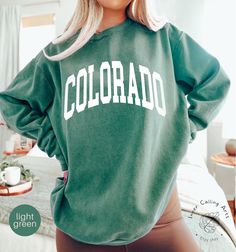 Comfort Colors® Colorado Sweatshirt, Boho, Colorado Crewneck, Colorado Women's Sweatshirt, Colorado Vintage Sweatshirt, Vintage Crewneck Hi, thank you so much for shopping with us! ❤️ ◦ ◦ ◦ ◦ ◦ size and material ◦ ◦ ◦ ◦ ◦ ◦ Comfort Colors® 1566 ◦ Adult Unisex Crewneck Sweatshirt ◦ 80% Ring Spun Cotton / 20% Polyester ◦ 3-end garment-dyed soft ring spun fleece with a 100% cotton face ◦ Comfort Colors garments are pre-shrunk during the garment dye process for almost no shrinkage at home ◦ Twill taped back neck for comfort and durability ◦ Half-moon neck patch on the back ◦ Relaxed fit, side seamed body ◦ The fabric is soft and pleasant to touch, has a subtle luxurious feel ◦ The way that we print our sweatshirts is Direct-to-Garment printing, meaning that the ink is printed INTO the sweatshi Green Pre-shrunk Relaxed Fit Sweatshirt, Green Relaxed Fit Pre-shrunk Sweatshirt, Green Collegiate Crew Neck Top, Collegiate Green Crew Neck Top, Green Sweater With Letter Print In Relaxed Fit, Green Relaxed Fit Sweater With Letter Print, Green Pre-shrunk Long Sleeve Top, Green Long Sleeve Fan Apparel Top, Green Collegiate Long Sleeve Sweatshirt