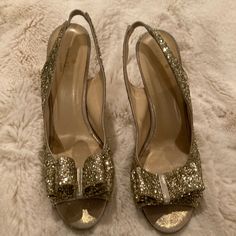 a pair of gold glitter shoes with bows on them