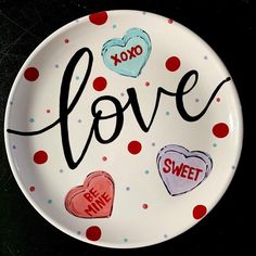 a plate with the word love written on it and hearts painted on it in different colors