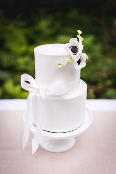 a three tiered white wedding cake with flowers on top