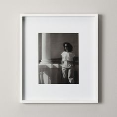 a black and white photo of a woman standing in front of a pillar with her hands on her hips