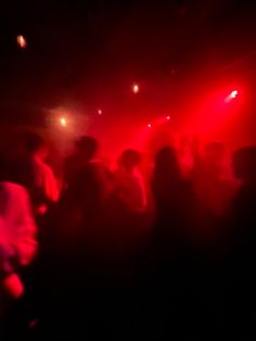 a group of people standing on top of a dance floor in front of red lights