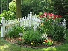 a white picket fence surrounded by flowers and trees