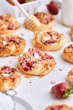 strawberry hand pies on a baking sheet with a honey dip being drizzled over them