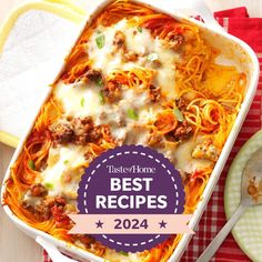 a casserole dish with meat and cheese on the side next to a plate of pasta