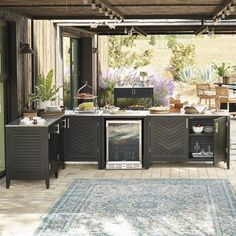 an outdoor kitchen and dining area is shown in this image, with blue rugs on the floor