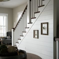 a living room filled with furniture and pictures on the wall next to a stair case