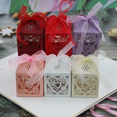 four small boxes with bows on them sitting on a table next to candy canes